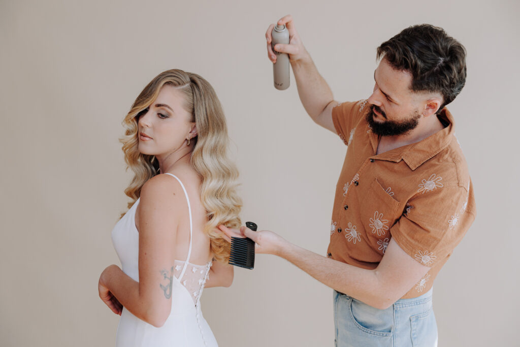 male hairdresser styling a blonde bride