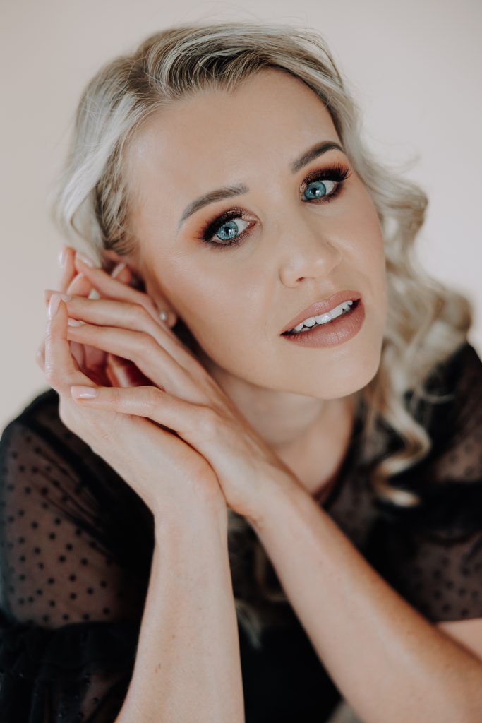 blonde female with black shirt in studio with a neutral backdrop