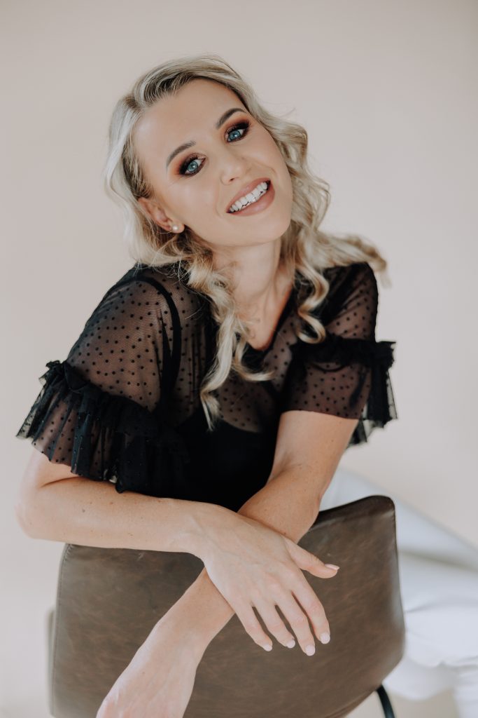 blonde female with black shirt in studio with a neutral backdrop