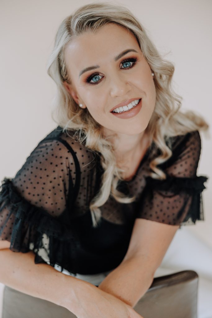 blonde female with black shirt in studio with a neutral backdrop