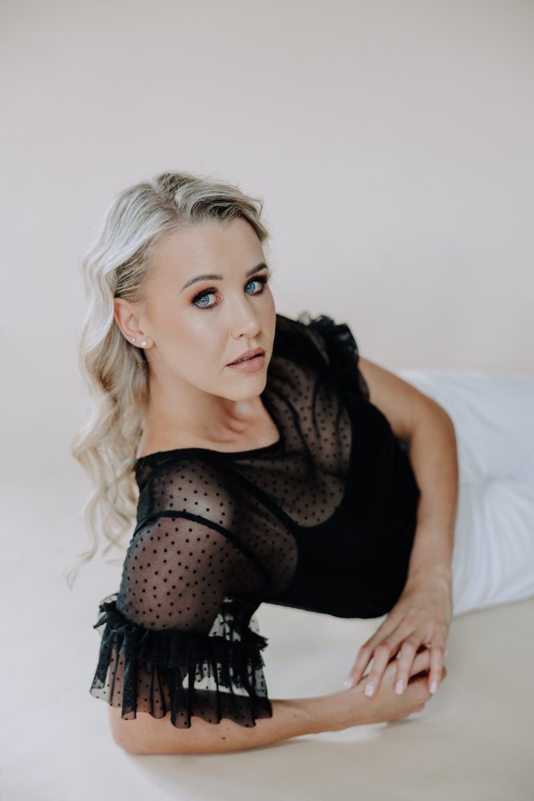 blonde female with black shirt in studio with a neutral backdrop