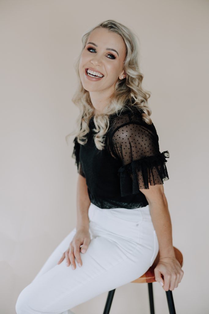 blonde female with black shirt in studio with a neutral backdrop